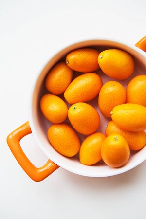 tasty kumquat in orange plate isolated on white background.の写真素材