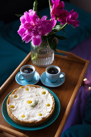 Breakfast in bed. Beautiful peonies, delicious cheesecake and two cups of coffee on a wooden tray.の写真素材