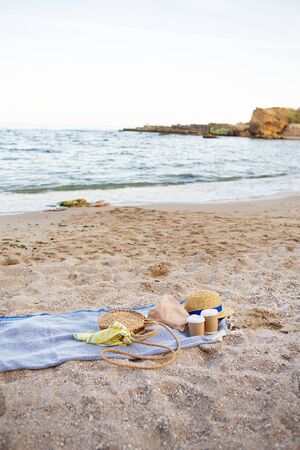 A blue plaid on which are plastic glasses with coffee, a bag, a hat on the seashoreの写真素材