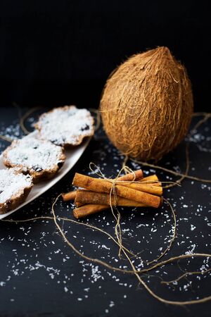 coconut muffins on a white plate with whole coconut and cinnamon sticksの写真素材