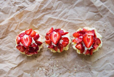 Very tasty muffins with fresh strawberries lie on kraft paper.の写真素材