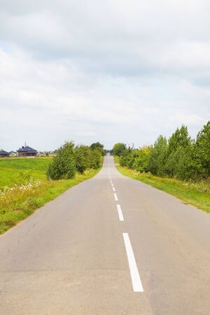 rural, asphalt road in a green field going out of the horizonの写真素材