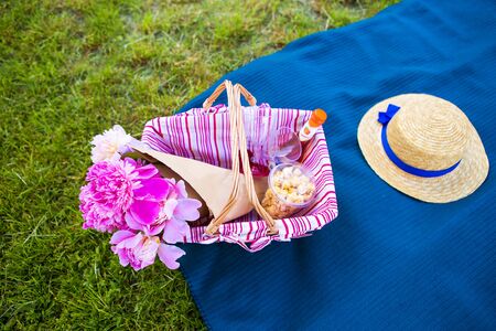 A basket with beautiful flowers and a straw hat on a plaidの写真素材