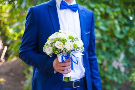 Beautiful wedding bouquet in hands of the groomの写真素材