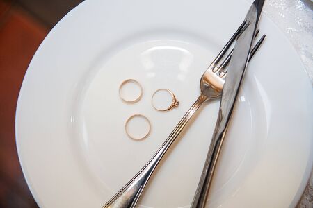 Tableware, a beautiful golden wedding ring on a white plateの写真素材