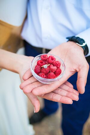 Wedding rings in a bowl with raspberries top viewの写真素材