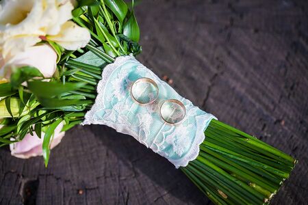 Wedding bouquet with rings on a tree stumpの写真素材