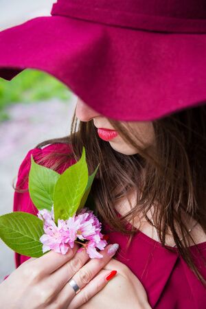 girl in a red dress holding sakura in handsの写真素材
