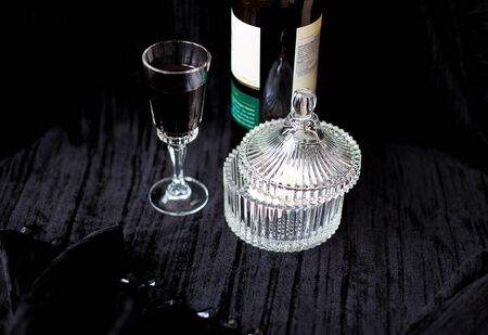 Sweets dishes, bottle and a glass of red wine on a black background.の写真素材