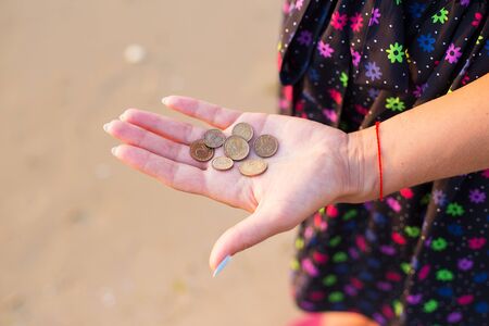 Girl holds coins to throw in the seaの写真素材
