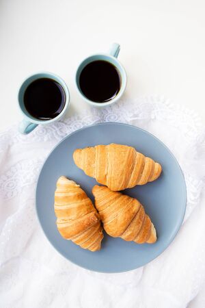 two cups of coffee with croissants on the background of laces on a white backgroundの写真素材