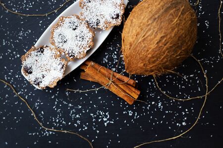 coconut muffins with chocolate and cinnamon on a black background and whole coconutの写真素材