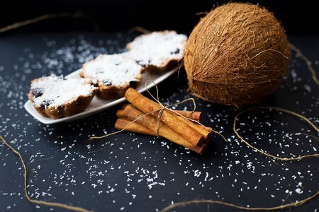 coconut muffins on a white plate with whole coconut and cinnamon sticksの写真素材