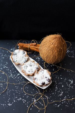 coconut muffins on a white plate with whole coconut and cinnamon sticksの写真素材