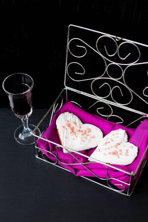 glass of wine and cookies in the form of heart lies in a casket.の写真素材