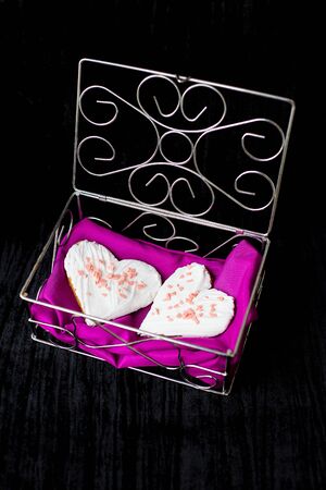 Cookies in the form of heart lies in a casket with pink cloth.の写真素材