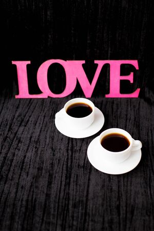 two cups of coffee on pink background inscription love.の写真素材