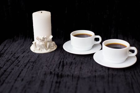 candle and two cups of coffee on a black background.の写真素材