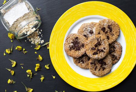 Oatmeal cookies with chocolate on a yellow plateの写真素材