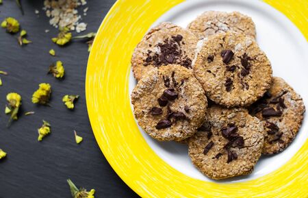 Oatmeal cookies with chocolate on a yellow plateの写真素材