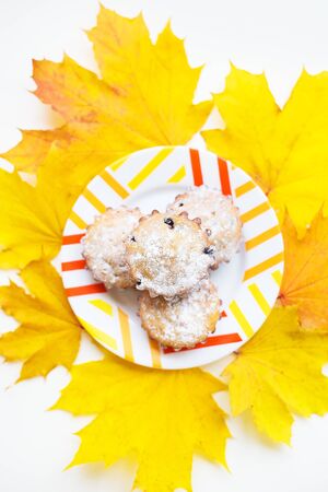colored cupcakes on a plate and yellow autumn leaves, close-upの写真素材