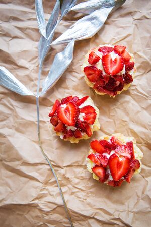 Beautiful cupcakes with strawberries along with a branch on kraft paper.の写真素材