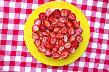 Bright and delicious strawberry cake on a red napkin in a cage.の写真素材