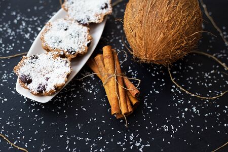 coconut muffins with chocolate and cinnamon on a black background and whole coconutの写真素材