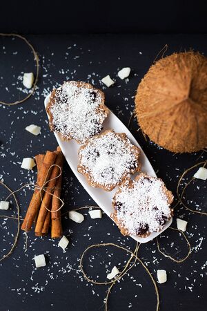 coconut muffins on a black background with cinnamon sticks and whole coconutの写真素材