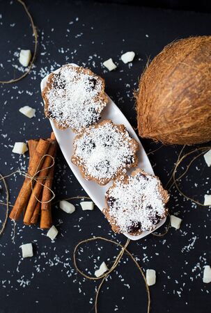 coconut muffins on a black background with cinnamon sticks and whole coconut slices and candiedの写真素材