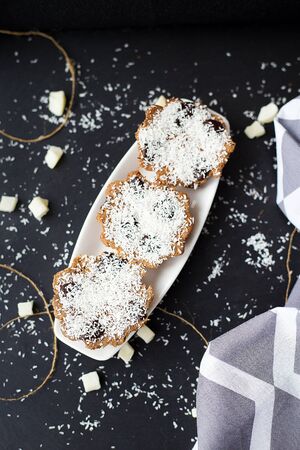 coconut muffins on a black background with candied coconut and gray clothの写真素材