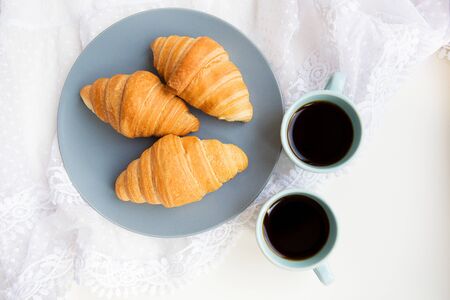 two cups of coffee with croissants on the background of laces on a white background, close-upの写真素材