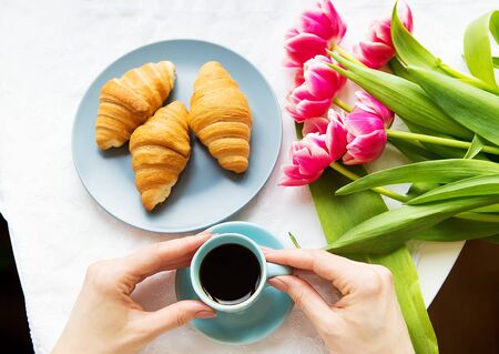 Girl with croissants and coffee, a bouquet of pink tulips, happy morning.の写真素材