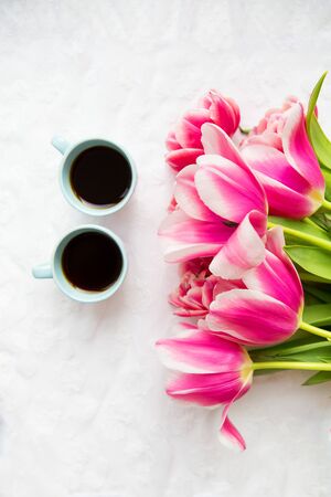 two cups of coffee and a bouquet of pink tulips.の写真素材