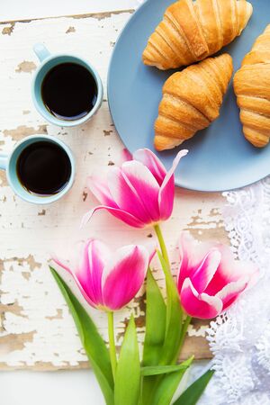 coffee, croissants and three beautiful pink tulips on old white table.の写真素材