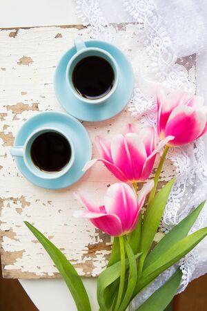 coffee, croissants and three beautiful pink tulips on old white table.の写真素材