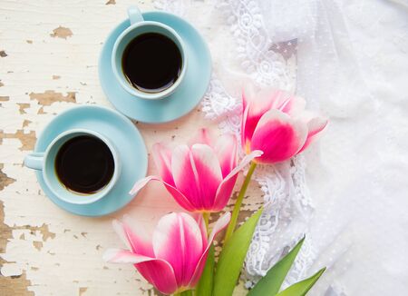 two cups of coffee and pink tulips on an old table.の写真素材