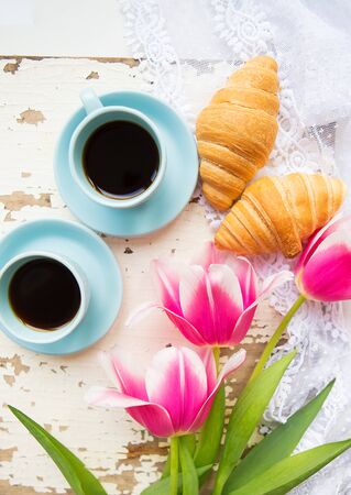 coffee, croissants and three beautiful pink tulips on old white table.の写真素材