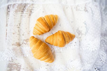 Beautiful and delicious croissants on the background of old laces and white table.の写真素材