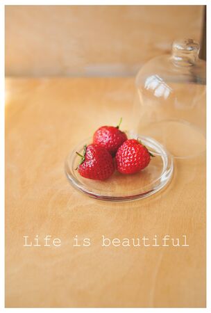 strawberries in a glass bowl on a wooden background, life is beautiful inscriptionの写真素材