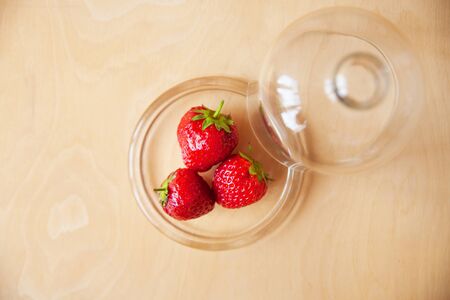 strawberries in a glass bowl on a wooden backgroundの写真素材