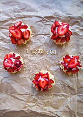 Bright cupcake with strawberries lies on craft paper, the inscription I love you. valentine cardの写真素材
