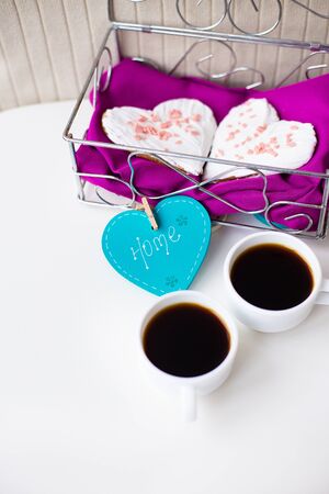 Cookies in a heart and two cups of coffee on the table that says home. valentine cardの写真素材