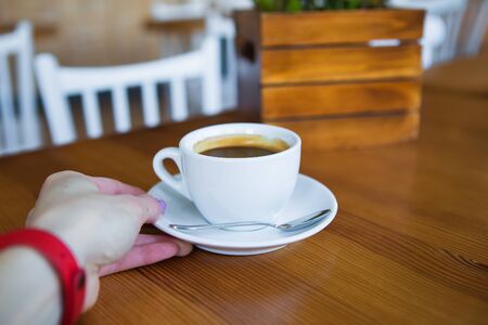 Coffee in a white cup stands on a wooden table, relax time with coffee.の写真素材