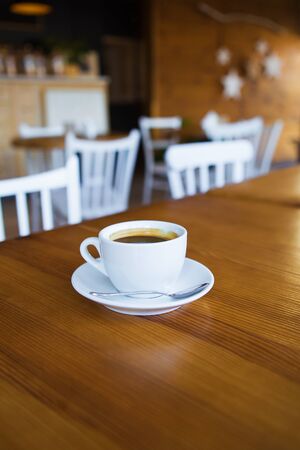 Coffee in a white cup stands on a wooden table, relax time with coffee.の写真素材