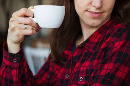 The girl is holding a cup of coffee. Close-up.の写真素材