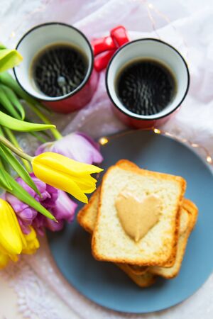 Lovely breakfast in bed. Black coffee, bright flowers, toast with peanut butterの写真素材