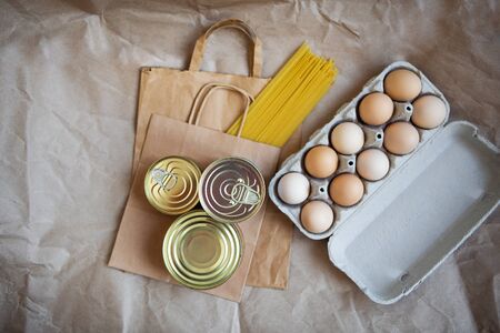Eggs, canned food, pasta, products in environmentally friendly craft packages. Vegetarian healthy organic foods from the market. Donation, help for those in need. View from above.の写真素材