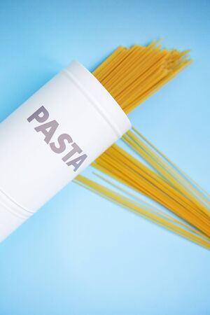 Pasta, italian dinner. Spaghetti in a tin can with the inscription pasta and scattered on a blue background. Place for an inscription.の写真素材