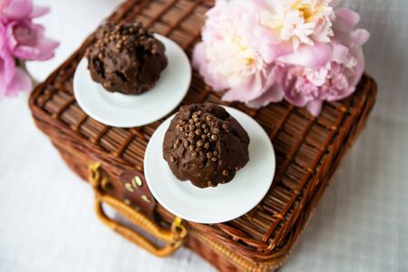 Chocolate muffins and beautiful pink peonies lie on a wooden suitcase. Beautiful composition.の写真素材